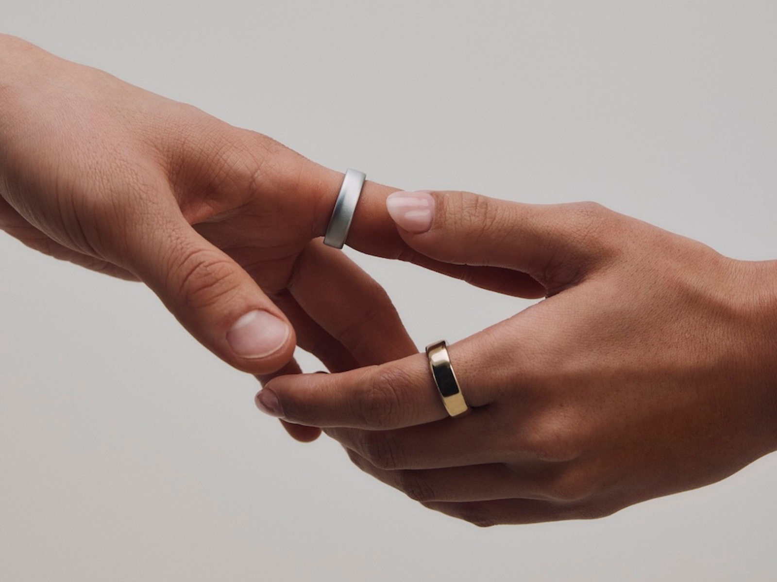 Oura Ring 5 in brushed silver and gold, worn on two hands